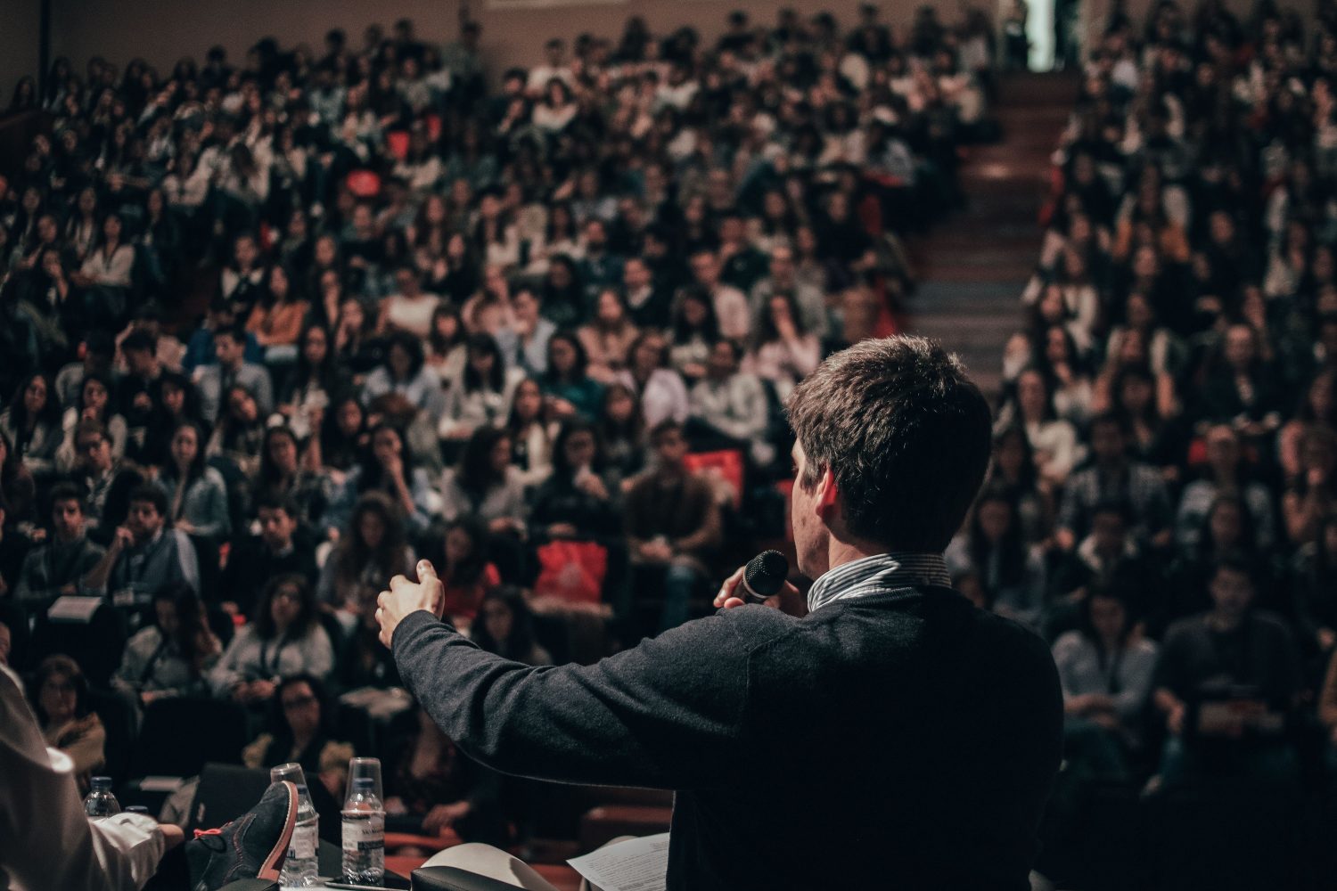 Un homme parle en public dans une salle devant beaucoup de gens
